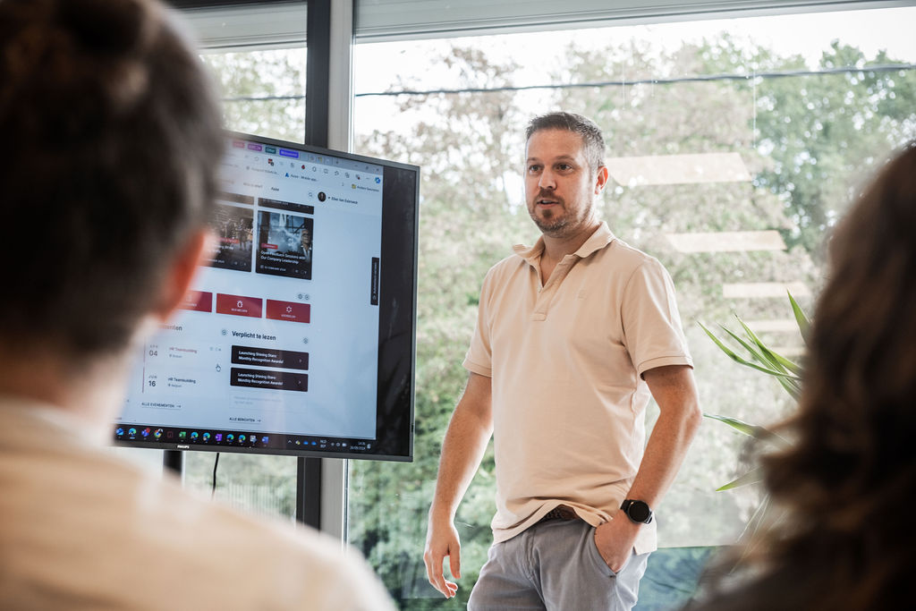 Un collègue montre l'intranet Involv sur un grand écran dans l'environnement Microsoft 365