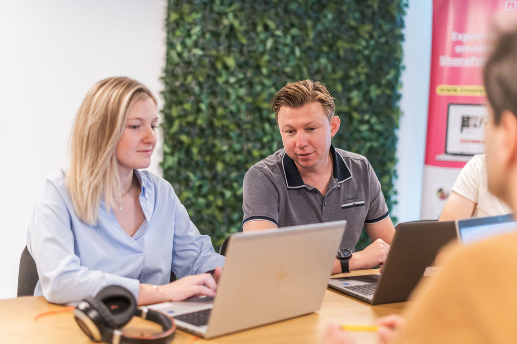 Two colleagues reviewing content together on their laptops